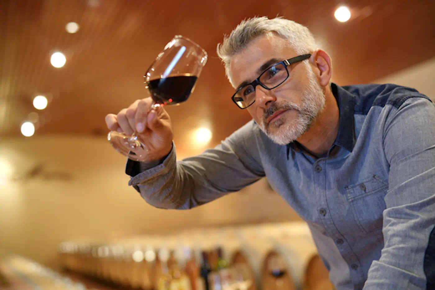 Man looking at the color and clarity of wine in his glass